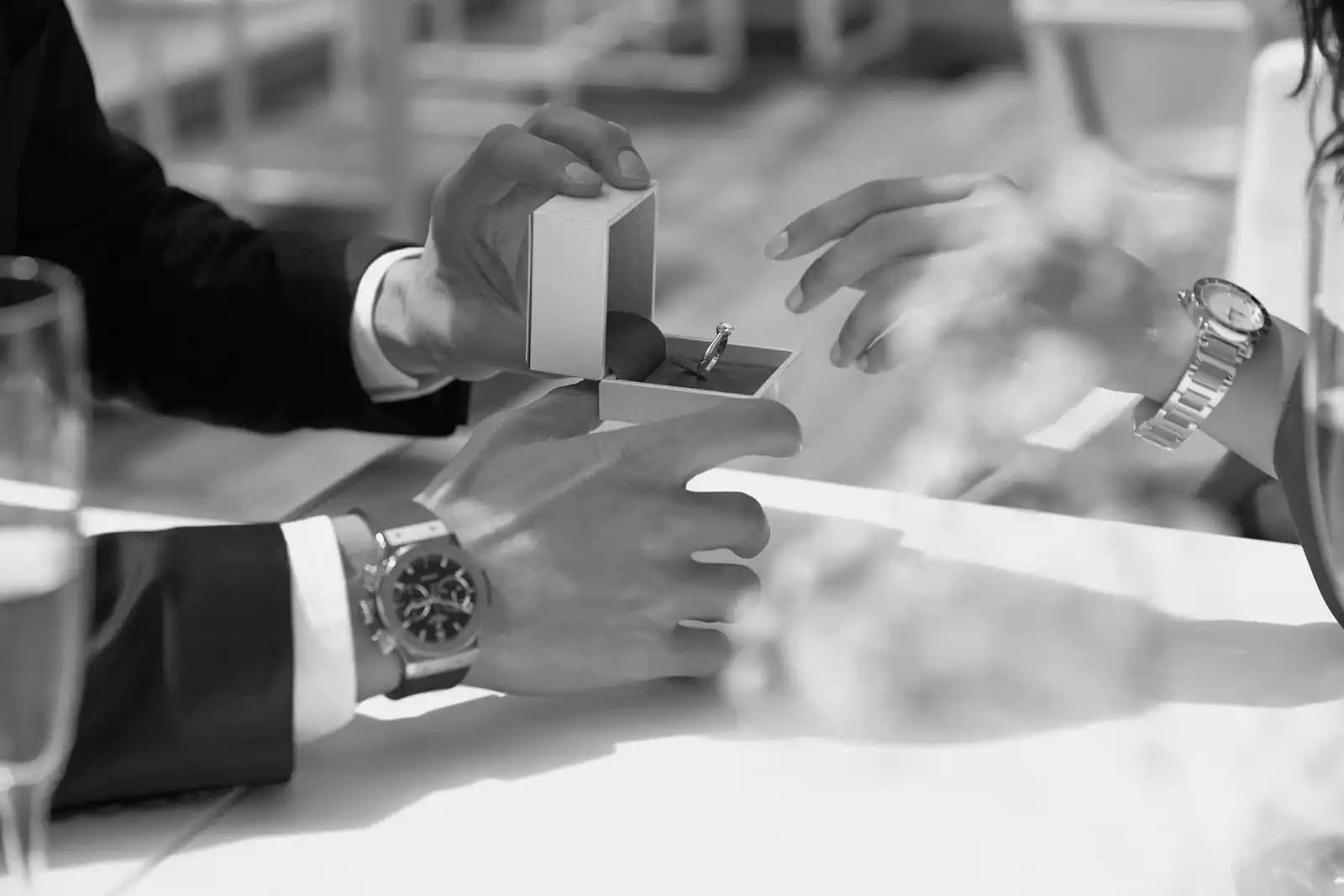 Detalle de manos con anillo de compromiso y relojes de él y ella